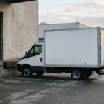 Box truck parked beside a loading dock as a worker opens the rear door